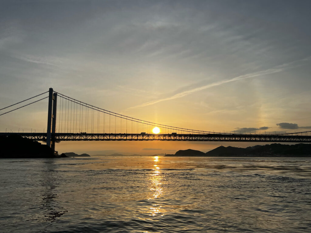 海上から見た瀬戸大橋に重なる夕陽